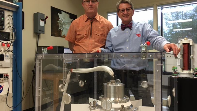 UES engineer Allen Tolston, left, and University of Dayton Research Institute scientist Chad Barklay, with a prototype power generator modeled after the one expected to power a NASA rover mission to Mars, in a photo taken in April 2017. THOMAS GNAU/STAFF