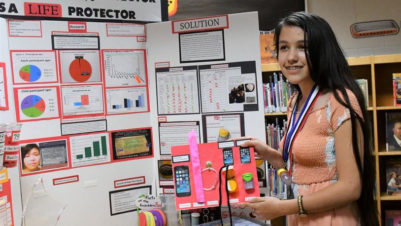 Jianna Nichols, 13, of Tipp City discusses her project board which received national recognition during an invention convention competition in Michigan in June. Contributed.