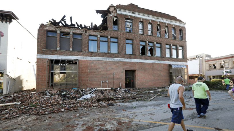 Local residents walk past a tornado-damaged building on Main Street, Thursday, July 19, 2018, in Marshalltown, Iowa. Several buildings were damaged by a tornado in the main business district in town including the historic courthouse. (AP Photo/Charlie Neibergall)