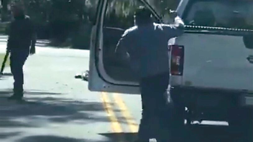 This image from video posted on Twitter Tuesday, May 5, 2020, purports to show Ahmaud Arbery lying on the road after being shot as Travis McMichael, left, holding a shotgun, and his father, Gregory McMichael, holding a handgun, approach him in a neighborhood outside Brunswick, Ga., on Feb. 23, 2020. The AP has not been able to verify the source of the video. (Twitter via AP) (AP)