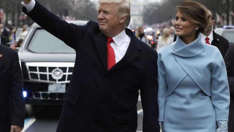 President Donald Trump waves as he walks with first lady Melania Trump during the inauguration parade on Pennsylvania Avenue in Washington. (AP Photo/Evan Vucci)
