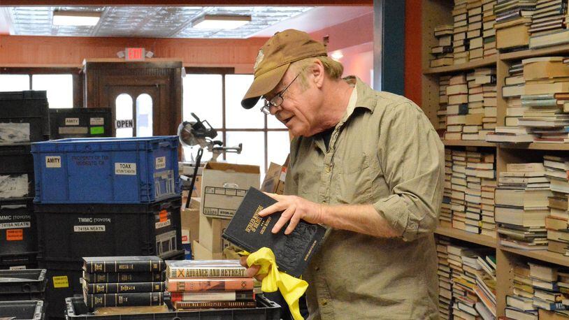Bill Jones works to organize thousands of books as he prepares for reopening of Browse Awhile Books in downtown Tipp City following a June fire. CONTRIBUTED