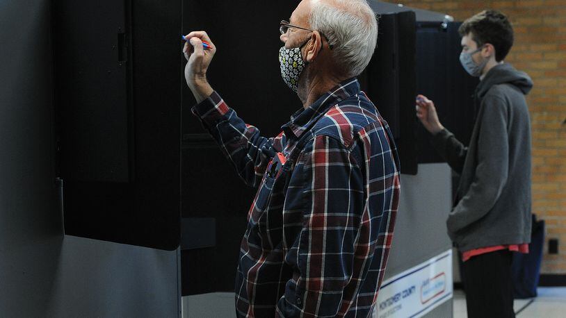 David Turpin, left, looks over his ballot while voting Tuesday Nov. 2, 2021 at the Central Christian Church in Kettering. MARSHALL GORBY\STAFF