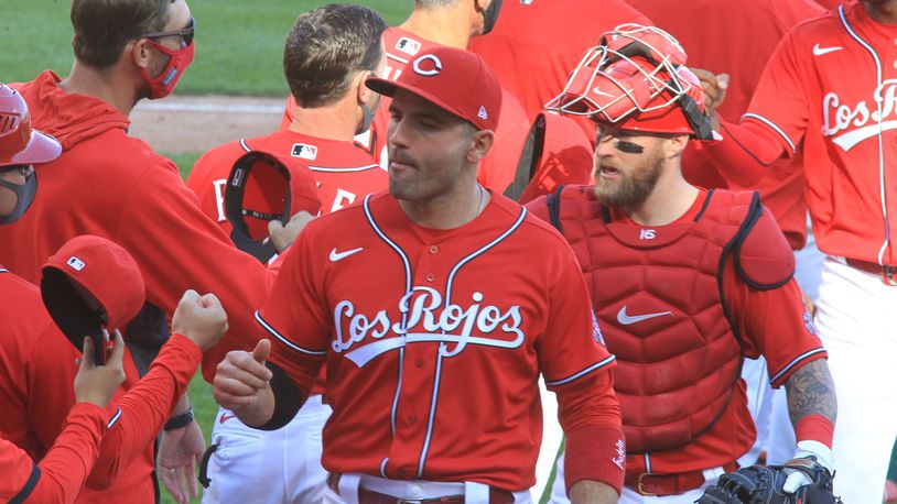 Joey Votto, center, and Tucker Barnhart, right, leave the field as the Reds celebrate a victory against the White Sox on Sunday, Sept. 20, 2020, at Great American Ball Park in Cincinnati. David Jablonski/Staff