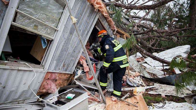 A rescue worker enters a hole in the back of a mobile home Monday, Jan. 23, 2017, in Big Pine Estates that was damaged by a tornado, in Albany, Ga. Fire and rescue crews were searching through the debris, looking for people who might have become trapped when the deadly storm came through. (AP Photo/Branden Camp)