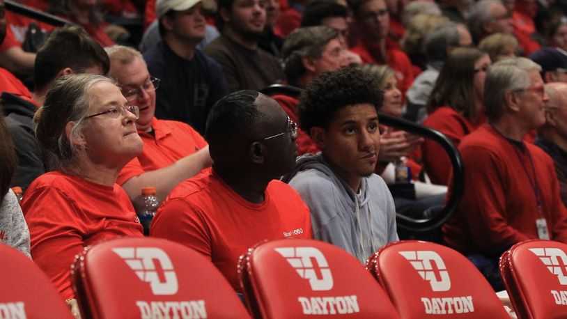 Zimife Nwokeji, right, sits with his parents Linda and Kennedy behind the Dayton bench on Saturday, Dec. 14, 2019, at UD Arena. David Jablonski/Staff