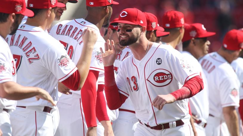 The Reds’ Jesse Winker slaps hands with teammates before a game against the Pirates on Opening Day on Thursday, March 28, 2019, at Great American Ball Park in Cincinnati.