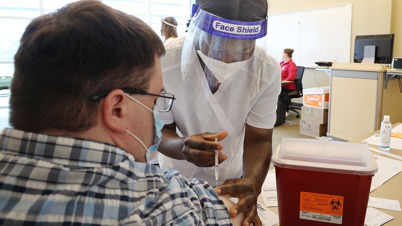 Vivian Adu, a nursing student at Clark State College, gives Andrew Deans a COVID vaccine injection during a clinic at the college a few months ago. BILL LACKEY/STAFF