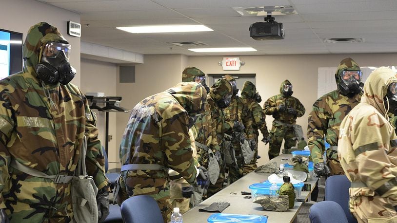 Airmen suit up in full mission oriented protective posture gear during a chemical warfare training class at the 88th Civil Engineer Squadron on Wright-Patterson Air Force Base. The gear protects from a toxic chemical, biological, radiological or nuclear environment. The course is a requirement for all personnel designated to deploy prior to departure. (U.S. Air Force contributed photo)