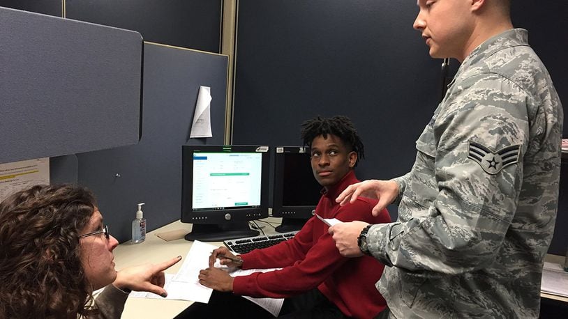 Stephen Oliver, a PALACE Acquire intern in electronic engineering, consults with Senior Airman Zachary Cinnamon (right) as he prepares a tax return for Amy Oyos, a retiree’s spouse and Air Force veteran Feb. 9 at Wright-Patterson Air Force Base’s Tax Center in Bldg. 70, Door 6, Area A. (Skywrighter photo/Amy Rollins)