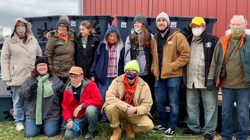 Chris Banks (bottom left) and volunteers with the Dayton Community Cat Project in front of over 20 cat shelters built on Nov. 13. LONDON BISHOP/STAFF