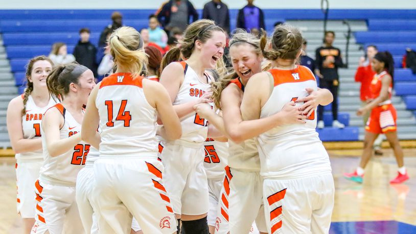 The Waynesville High School girls basketball team celebrates after beating Purcell Marian 39-35 in a Division III regional final on Saturday afternoon at Springfield High School. The undefeated Spartans (26-0) advanced to the D-III state tournament for the first time since 2005. CONTRIBUTED PHOTO BY MICHAEL COOPER