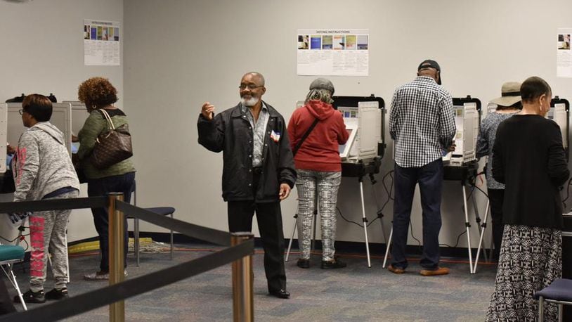 Volunteer Alfred Leblanc (center) directs early voters at the Gwinnett County Voter Registrations and Elections Office in Lawrenceville on Thursday, October 18, 2018.
