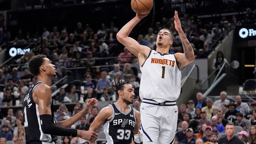 Denver Nuggets forward Michael Porter Jr., front right, shoots over San Antonio Spurs center Victor Wembanyama, left, and guard Tre Jones (33) during the first half of an NBA basketball game in San Antonio, Friday, April 12, 2024. (AP Photo/Eric Gay)