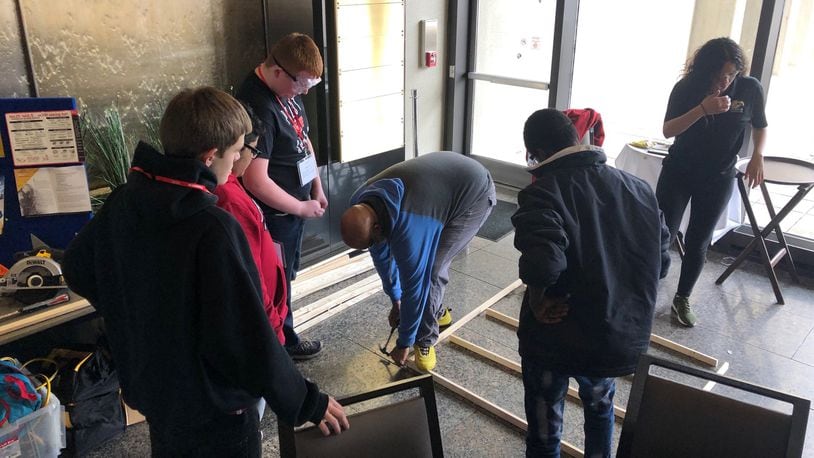 Keith Beason (center), who teaches construction classes at Dayton’s Ponitz Career Tech Center, demonstrates carpentry framing skills to eighth-graders at a Dayton Public Schools career exploration event Tuesday, Jan. 21, 2020, at Sinclair Community College. JEREMY P. KELLEY / STAFF