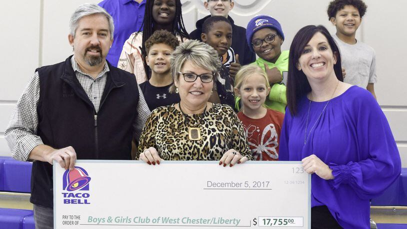 From left are Todd and Rebecca Wilber of CTI Restaurants, Inc. and Bridget Graber, CEO of the Boys & Girls Club of West Chester/Liberty, who hold a check for $17,755 to benefit youth club programs. Back row, left, is Dave Lindeman, club COO, with club members. CTI Restaurants raised the funds from its Butler and Warren County Taco Bell restaurants. CONTRIBUTED