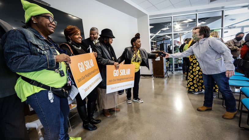 A group from the Dayton NAACP pose for pictures holding go solar signs after a presentation about solar co-op that is available in the Miami Valley. JIM NOELKER/STAFF