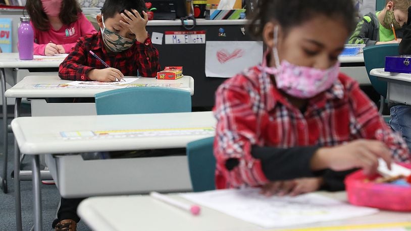 With masks and desks spaced apart, young students at Simon Kenton Elementary School in Xenia work on classwork Feb. 19, 2021. BILL LACKEY/STAFF