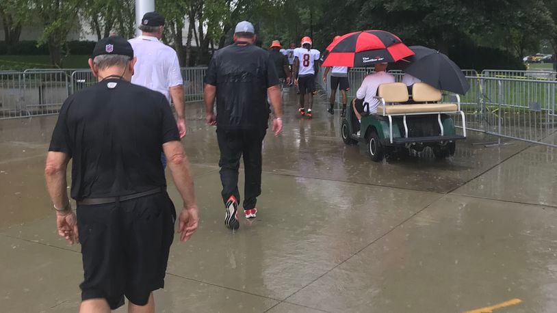 Cincinnati Bengals players, coaches and team owner Mike Brown (on golf cart) head for cover after heavy rains delayed practice for 30 minutes Tuesday. JAY MORRISON/STAFF