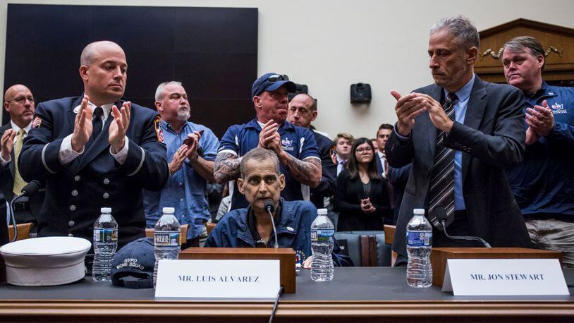 WASHINGTON, DC - JUNE 11: Retired Fire Department of New York Lieutenant and 9/11 responder Michael O'Connelll, left, FealGood Foundation co-founder John Feal,  center, and former Daily Show Host Jon Stewart, right, applaud following testimony from Retired New York Police Department detective and 9/11 responder Luis Alvarez during a House Judiciary Committee hearing on reauthorization of the September 11th Victim Compensation Fund on Capitol Hill on June 11, 2019 in Washington, DC.