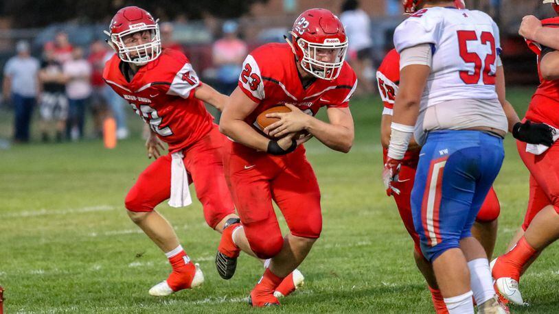Milton-Union quarterback Nathan Brumbaugh hands the ball off to Bulldogs running back Andrew Lambert during their game against Northwestern on Sept. 13 at Memorial Stadium. The Bulldogs won 27-21. CONTRIBUTED PHOTO BY MICHAEL COOPER