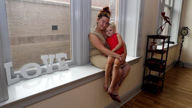 Brittany Jones sits with her daughter, Emma, in one of the windows in her new studio called, Make Our Photo Shine, in the Bushnell Building Friday. Bill Lackey/Staff
