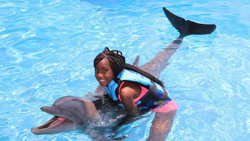 Thabisile “Thabie” Hadebe, 11, of Troy hugs a dolphin in Panama City, Fla. CONTRIBUTED
