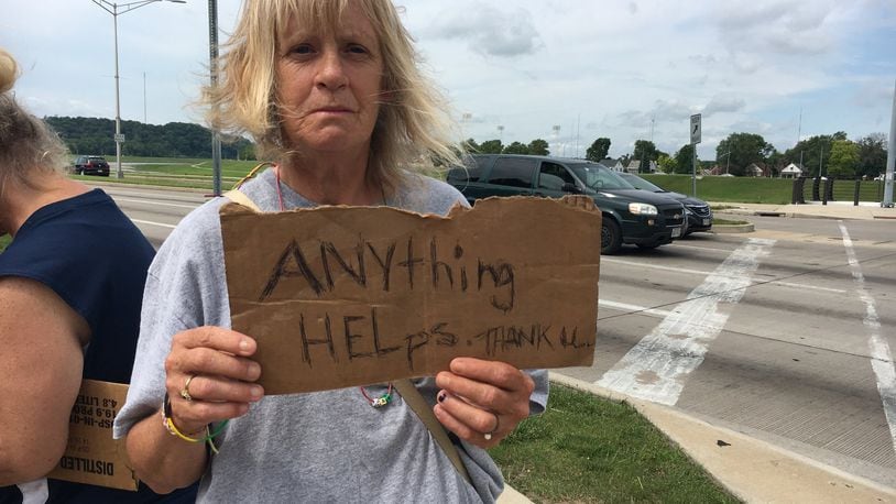 Abigail O’Neil, holding a sign at the intersection of Stewart Street and Patterson Boulevard, pulled up her sleeves to show she has no needle marks. “I’m no drug addict. You’re not going to find one needle mark except where a doctor took blood,” she said.