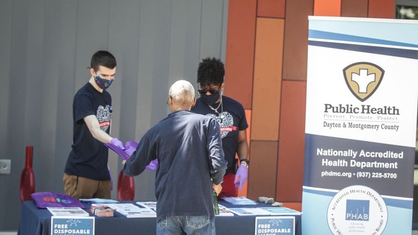 Matt Fisher, left, and Stacy Shern with the COVID-19 Community Health Equality Education and Outreach Team, handout free masks at the Dayton Metro Library on Philadelphia Drive on Thursday, Aug. 6, 2020. Jim Noelker/Staff