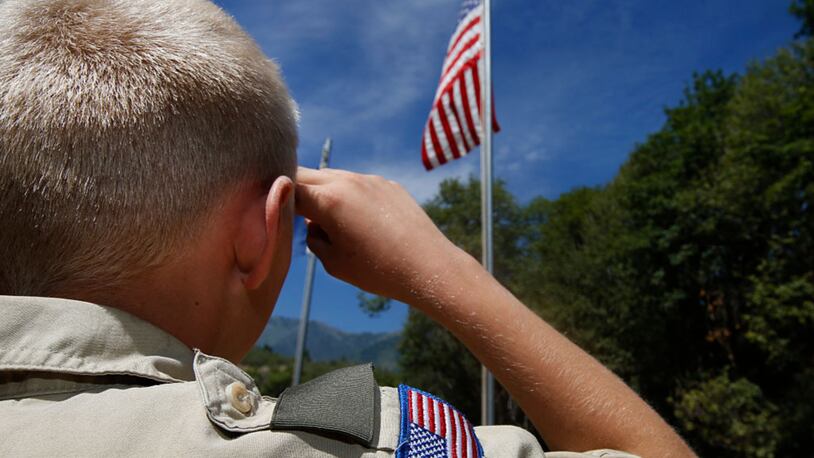 A Boy Scout salutes the American flag at camp.