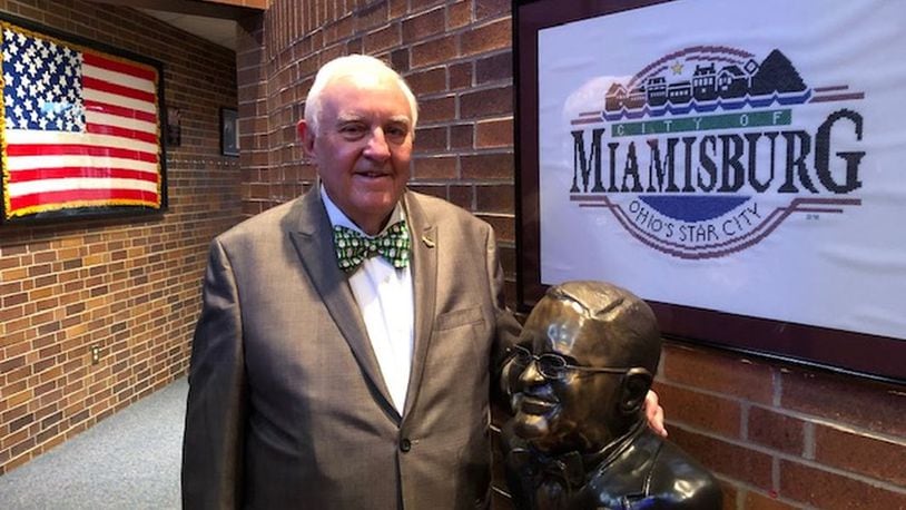 Former Miamisburg Mayor Dick Church Jr. stands in city council chambers next to a bust of him. Church ended his seven-term run as mayor when he retired in December 2019. NICK BLIZZARD