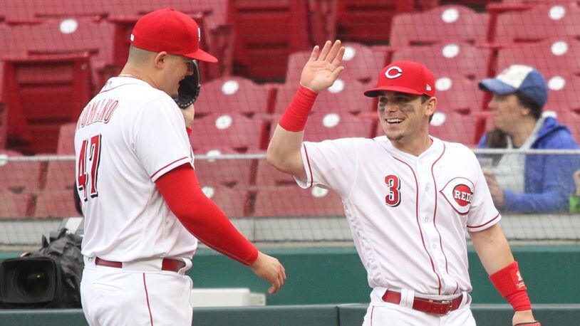 Reds second baseman Scooter Gennett, right, gives a high five to Sal Romano during a game against the Braves on April 23, 2018, at Great American Ball Park in Cincinnati.