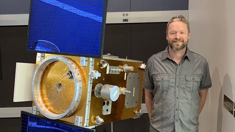 Daniel Engelhart, of Assurance Technology Corp., displays a scale model of satellite XSS-11, which uses Kapton to manage the internal temperature of the satellite. Electron irradiation alters the optical and mechanical properties of the material, leading to non-ideal spacecraft thermal management. (Courtesy photo)