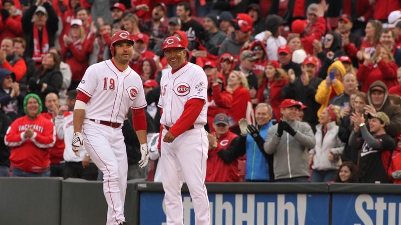 The Reds’ Joey Votto, left, and first-base coach Freddie Benavides smile after Votto drove in the go-ahead runs in the eighth inning against the Phillies on Opening Day on Monday, April 4, 2016, at Great American Ball Park in Cincinnati. David Jablonski/Staff
