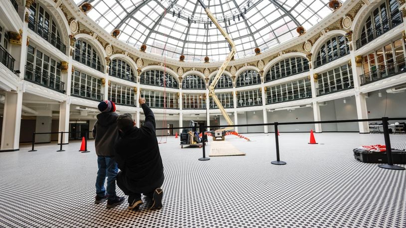 A father and son watch a worker put up lights at the Dayton Arcade on Thursday, Feb. 24, 2022. JIM NOELKER/STAFF