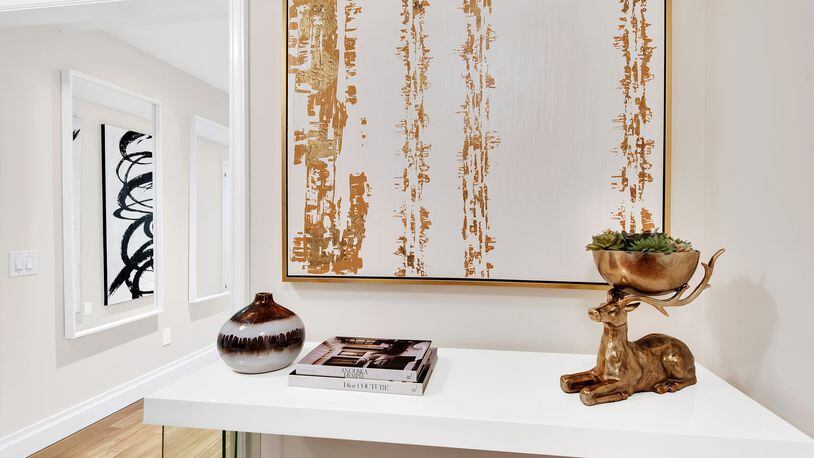 Gold artwork paired with a gold accent piece helps make this entry area shine. (Design Recipes)