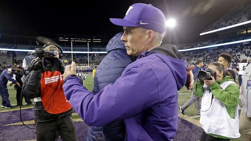 In this photo taken Saturday, Oct. 7, 2017, an ESPN video operator, left, looks on as Washington head coach Chris Petersen, right, embraces California head coach Justin Wilcox after their NCAA college football game ended shortly before 11 p.m., in Seattle. Petersen has moved on from the debate over Pac-12 After Dark, those late-night televised conference games that end in the wee hours on the East Coast. The issue was amplified in a not-so-good way over the weekend when Kirk Herbstreit said on ESPN's College Game Day that Petersen "should be thanking ESPN for actually having a relationship." (AP Photo/Elaine Thompson)