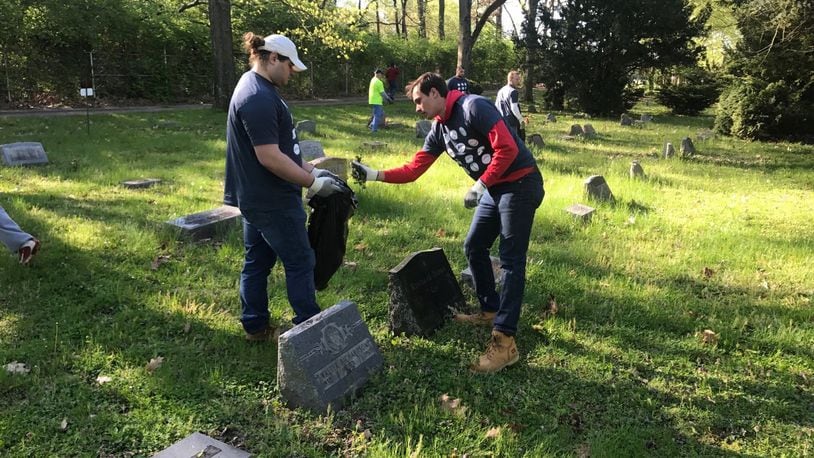 Dayton football players junior offensive lineman Ryan Culhane (left) and senior quarterback Will Bobek (right) clean up Ray Brown’s grave Saturday. Tom Archdeacon/CONTRIBUTED