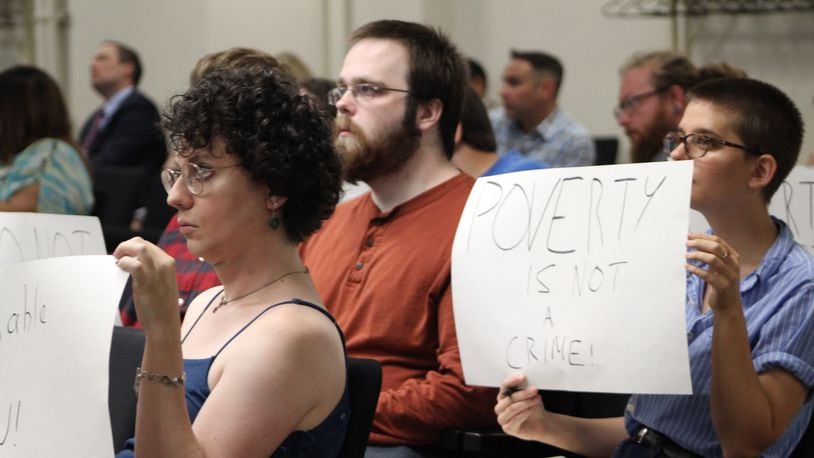 A group of citizens held up signs and spoke out against Dayton’s ordinance that will restrict panhandling and other pedestrian activities along 51 roadways. CORNELIUS FROLIK / STAFF