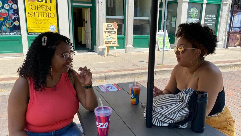 Donna Hill, left, and Bri Dudley, right, sit at one of the outdoor drinking area tables in the Oregon District on Saturday, July 3. Eileen McClory / Staff