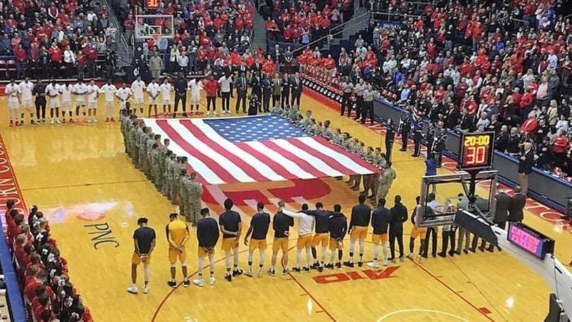 Wright-Patterson Band of Flight vocalist Staff Sgt. Joanne Griffin sings the national anthem while the base Honor Guard presents the colors, and students from the United States Air Force School of Aerospace Medicine and University of Dayton ROTC hold a large U.S. flag in the center of the court during the pregame ceremonies at a University of Dayton men’s basketball game in November 2018. (Contributed photo)