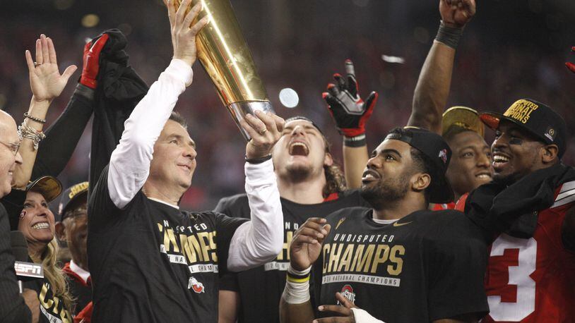 Ohio State's Urban Meyer hoists the trophy as Joey Bosa, Ezekiel Elliott and Tyvis Powell watch hafter beating Oregon in the national championship game on Monday, Jan. 12, 2015, at AT&T Stadium in Arlington, Texas.