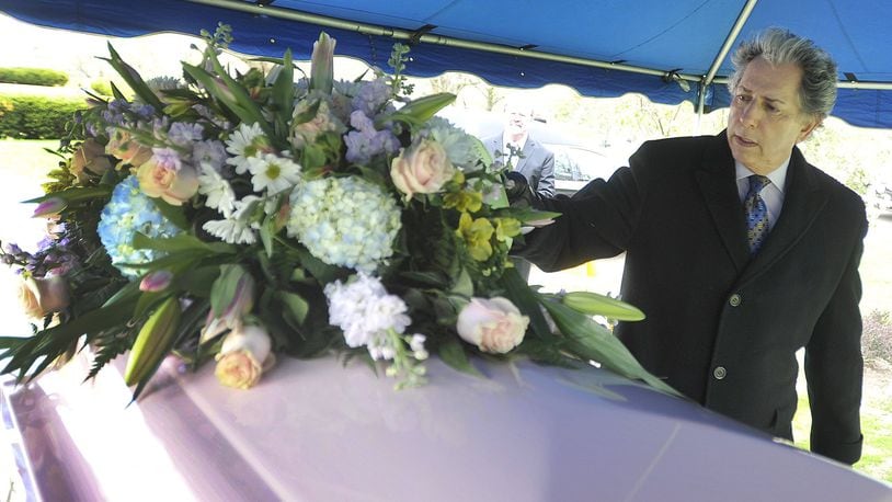 Funeral Home owner Larry Glickler places flowers on a casket at a recent funeral. MARSHALL GORBYSTAFF