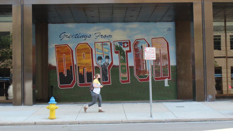 A citizen on Tuesday walks past a mural on the side of a downtown Dayton office building. CORNELIUS FROLIK / STAFF