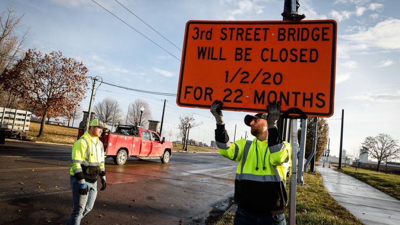 Kevin Kirk, left, and Wes Minton remove road closed signs from the newly rebuilt Third Street bridge in Dayton on Thursday Dec. 2, 2021. JIM NOELKER/STAFF