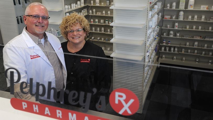 Bruce Pelhrey, RPh, with his wife Lisa, stand behind the corner of their new business, Pelphrey's Pharmacy, located at 7208 Tayorsville Road in Huber Heights. MARSHALL GORBY\STAFF