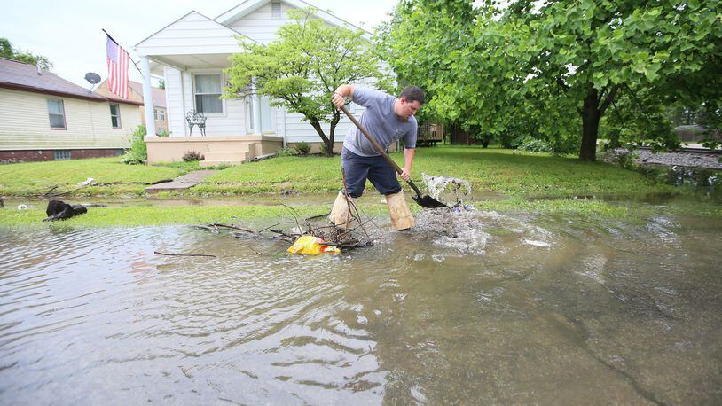 Hamilton city worker Colt Mann works to clear a storm drain along Kenworth Avenue after heavy rains caused flash flooding on the west side of Hamilton in 2016.