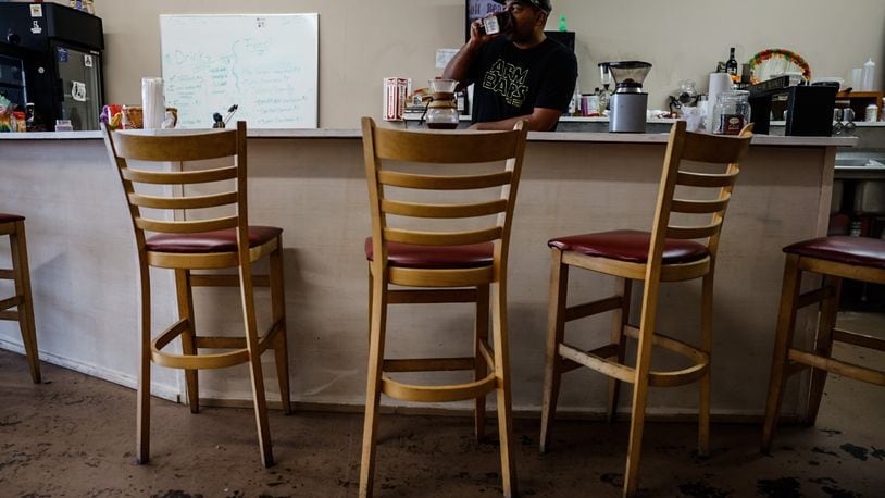 Rob Dejene owner of Nimbus Comic Cafe serves up coffee at his shop on East Main Street in Trotwood. JIM NOELKER/STAFF