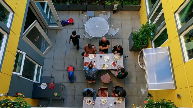 Residents of Capitol Hill Urban Cohousing talk over dinner in the central courtyard. We designed the building so all homes face the courtyard, says architect Grace Kim, who lives here with her family. When we were studying cohousing in Denmark, in general, Danish courtyards are in the center, so you d have shared outdoor space. Often the inside is a yellow/warm color. In the Pacific Northwest, it s really gray. Our concern was for light; it s nice to reflect happy yellow. Yellow goes through the common spaces. (Erika Schultz/The Seattle Times/TNS)