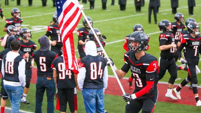 Franklin’s Kyle Rickard waves the American flag as the team takes the field to play visiting Edgewood in a Week 2 game. GREG LYNCH / STAFF